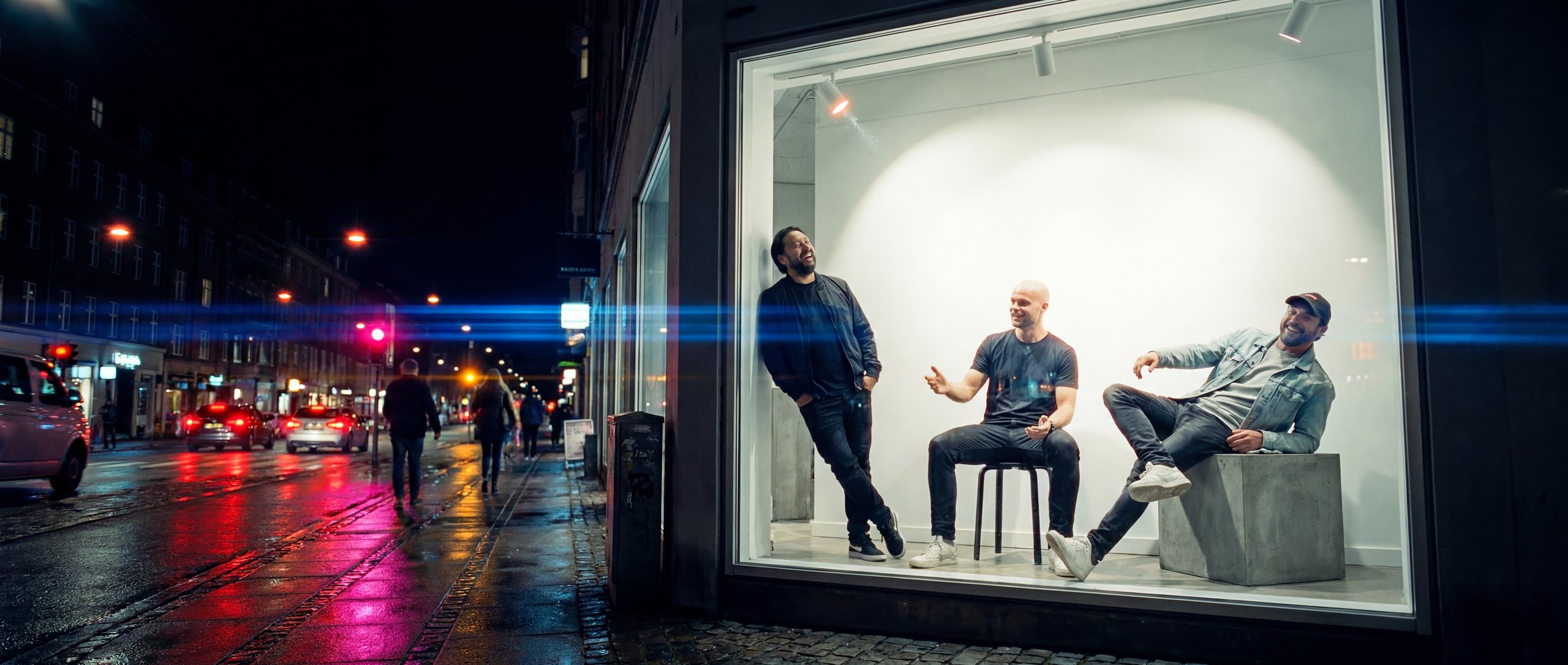 The Front — Robin, Jordy and Timo in a lit shop-window display at night